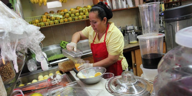 Celina Alvarez, 51, works at Jugueria de regreso al Eden, her shop in the Queens borough of New York, Monday Aug. 3, 2015. As a campaign to raise the minimum wage as high as $15 has rolled to victory in such places as Seattle, Los Angeles and New York, it has bumped up against a harsh reality: Plenty of scofflaw businesses donât pay the legal minimum now and probably wonât pay the new, higher wages either. (AP Photo/Tina Fineberg)