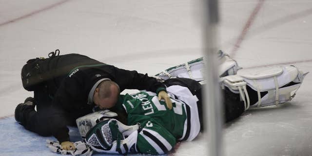 Dallas Stars goalie Kari Lehtonen (32) is tended to after being hit by Minnesota Wild left wing Erik Haula (56) at American Airlines Center in Dallas March 8, 2014. (AP Photo/The Dallas Morning News, Nathan Hunsinger