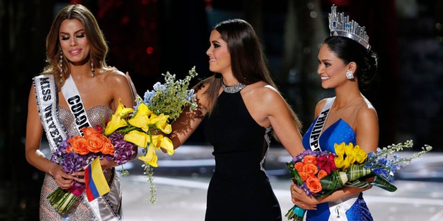 Former Miss Universe Paulina Vega takes away the flowers and sash from Miss Colombia Ariadna Gutierrez before giving them to Miss Philippines Pia Alonzo Wurtzbach on Sunday, Dec. 20, 2015.