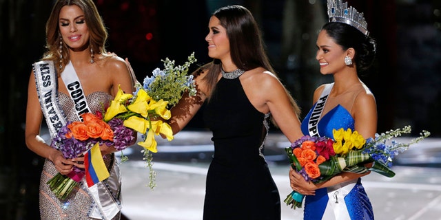 Former Miss Universe Paulina Vega takes away the flowers and sash from Miss Colombia Ariadna Gutierrez before giving them to Miss Philippines Pia Alonzo Wurtzbach on Sunday, Dec. 20, 2015.
