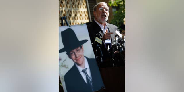 Then-New York assemblyman Dov Hikind standing near a photograph of Aaron Sofer, in Lakewood, N.J., in 2014. Sofer, missing at the time, later was found dead.