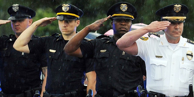 Hattiesburg police officers salute their fallen fellow officer Benjamin Deen as the hearse carrying his body arrives at the Hulett Winstead Funeral Home in Hattiesburg, Miss., Monday, May 11, 2015. Officers Deen and Liquori Tate were gunned down Saturday night during a traffic stop near the East 4th and Bouie Street intersection. (Photo by Ryan Moore/WDAM-TV via AP)