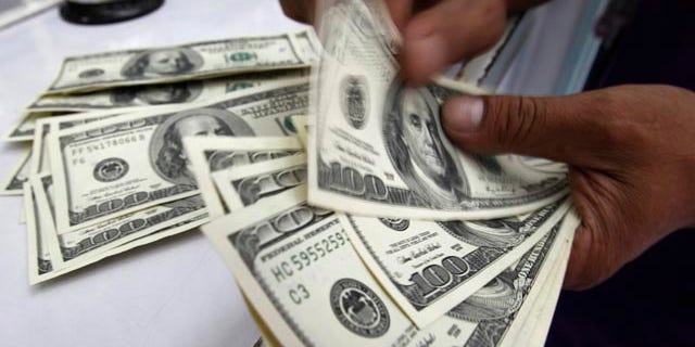 A worker counts U.S. dollar bills at a money changer in Manila, Philippines, Aug. 10, 2011.