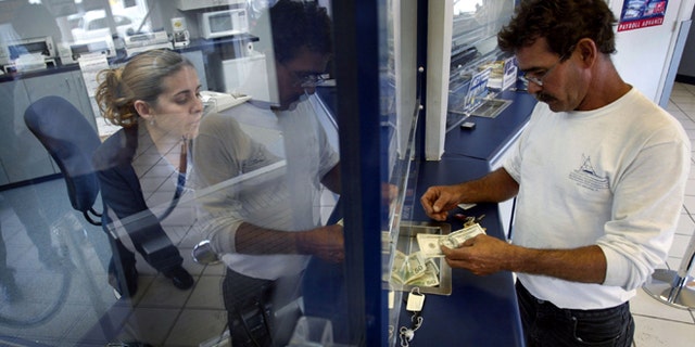MIAMI - MAY 11: Rachel Garcia takes cash from Ramon Cruz (R) for a $300 wire transfer via Western Union to Cuba, which Cruz left three years ago, the money will be received by his mother still living on the island May 11, 2004 at a Check Cashing USA store in the Little Havana neighborhood in Miami, Florida. The Cuban government announced that many sales in U.S. dollars would be suspended indefinitely. The government blamed the new measure on the Bush Administration's decision last week to tighten trips and cash remittances to the island. (Photo by Joe Raedle/Getty Images)