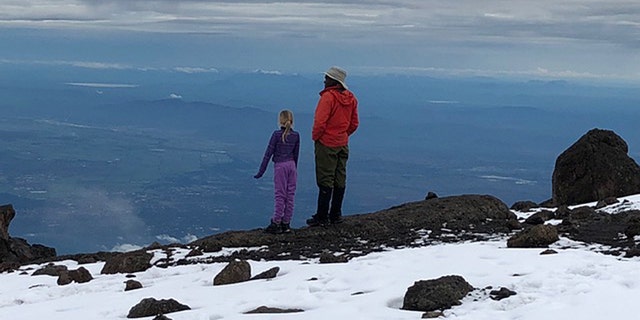 Montannah and their tour guide reflect at the top of the mountain.
