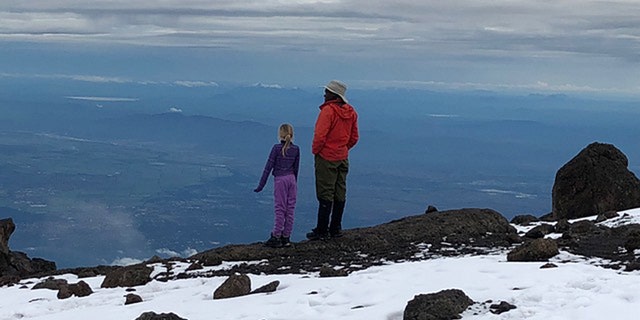 Montannah and their tour guide reflect at the top of the mountain.