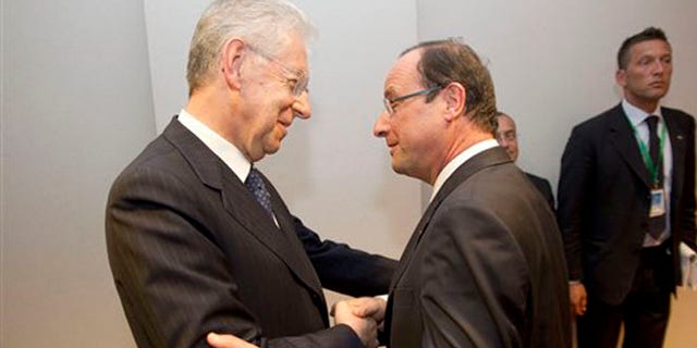 May 30, 2012: Italy's Prime Minister Mario Monti, left, shakes hands with French President Francois Hollande, right, prior to a bilateral meeting on sideline of an EU summit, at the European Council building in Brussels.