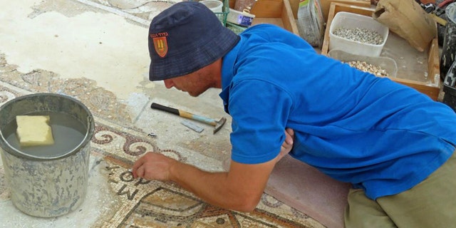 A worker of the Israel Antiquities Authority conserving the mosaic.