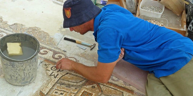 A worker of the Israel Antiquities Authority conserving the mosaic.