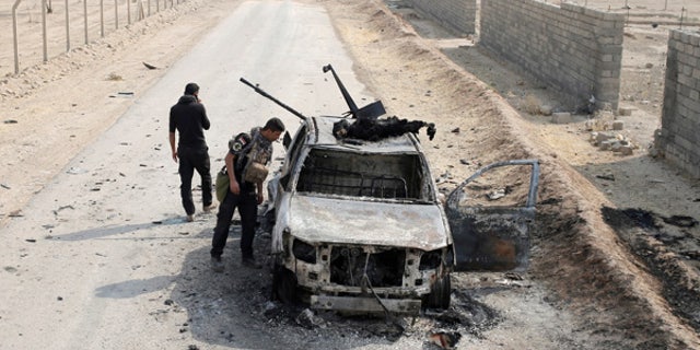 Iraqi Special Forces soldiers looks at a destroyed Islamic State vehicle in a village near Mosul, Iraq.