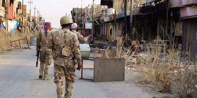 Soldiers from the Nineveh Plain Protection Unit search the recently reclaimed village Qaraqosh, located about 20 miles south of Mosul.