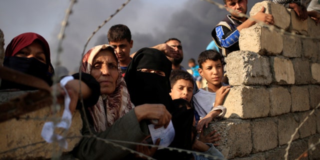 Newly displaced people wait as they complain about what they say is a lack of humanitarian aid outside the processing center in Qayyara, south of Mosul, Iraq.