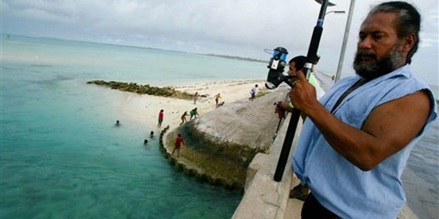 FILE - In this March 30, 2004 file photo, a man fishes on a bridge on Tarawa atoll, Kiribati.