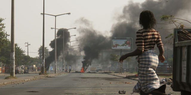 September 2: A woman passes nearby burning tires in a street in Maputo, Mozambique. (AP)