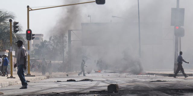September 1: People walk past barricades of burning tires in Maputo, Mozambique after police opened fire on stone-throwing crowds who were protesting rising prices in this impoverished country. (AP)