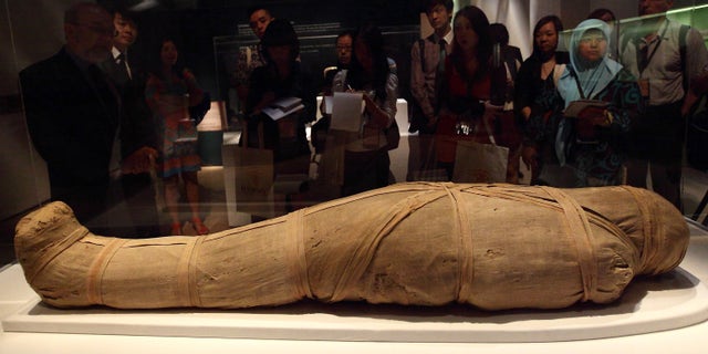 SINGAPORE - APRIL 25: (NOT FOR COMMERCIAL USE) Members of the media look at the Mummy of Shepenmehyt exhibit during a media preview of the Mummy: Secrets of the Tomb exhibition at ArtScience Museum on April 25, 2013 in Singapore. The exhibition includes more than 100 artifacts and six mummies from the heralded ancient Egyptian collection of the British Museum. Among the mummies displayed is the Egyptian temple priest, Nesperennub who lived 3,000 years ago. The exhibition will run from April 27 till November 4, 2013. (Photo by Suhaimi Abdullah/Getty Images)