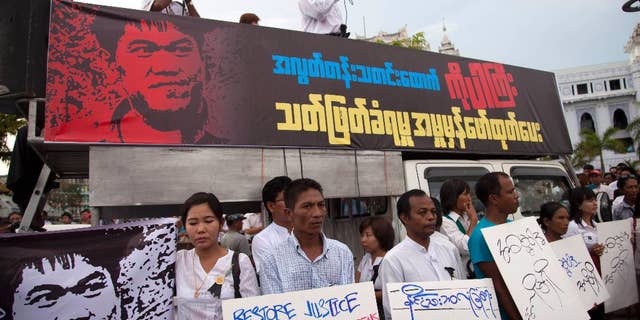FILE - In this Oct. 26, 2014 file photo, Min Ko Naing, right on vehicle, a leader of Myanmar Prominent 88 Generation Students Group, speaks as activists hold placards during a protest against the killing of a freelance journalist, outside the city hall in Yangon, Myanmar. Myanmar's army on Oct. 4 shot dead Aung Kyaw Naing who was detained while covering clashes between the army and ethnic Karen rebels in Mon state in September. The body of the freelance journalist shot by Myanmar's army show signs that he was tortured before he died, the wife of the journalist said Thursday, Nov. 6, 2014. (AP Photo/Khin Maung Win, File)