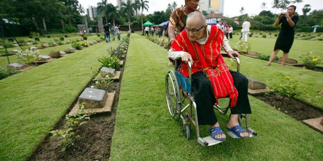 World War II veteran Saw Berny, who is ethnic Karen, looks at a gravestone as he attends a ceremony to mark the 70th anniversary of the end of World War II at Hanthawaddy War Cemetery in Yangon, Myanmar, Saturday, Aug. 15, 2015. Karen fought courageously behind Japanese lines with Seagrim, a lanky, eccentric and exceptional guerrilla leader. (AP Photo/Khin Maung Win)