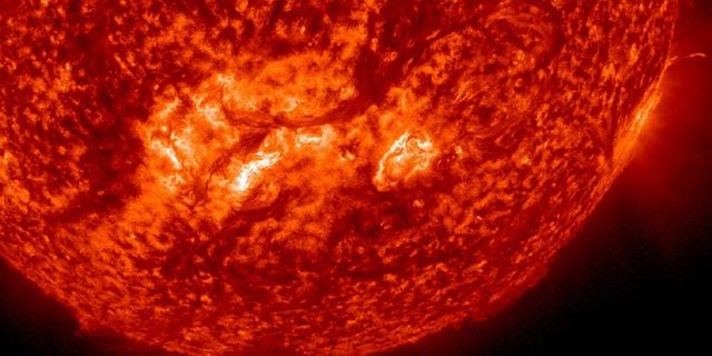 A very long, whip-like solar filament extends over half a million miles in a long arc above the suns surface.