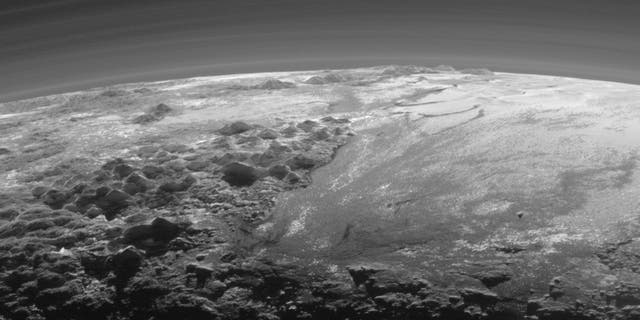 The smooth expanse of the informally named Sputnik Planum (right) is flanked to the west (left) by rugged mountains up to 11,000 feet high, including the informally named Norgay Montes in the foreground and Hillary Montes on the skyline. The backlighting highlights more than a dozen layers of haze in Pluto’s tenuous but distended atmosphere. The image was taken from a distance of 11,000 milesto Pluto; the scene is 230 miles across.