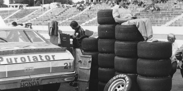 MARTINSVILLE, VA 1980: Driver Neil Bonnett uses a stack of Goodyear tires as a makeshift easy chair as he watches practice for a NASCAR Cup race at Martinsville Speedway. (Photo by ISC Images & Archives via Getty Images)