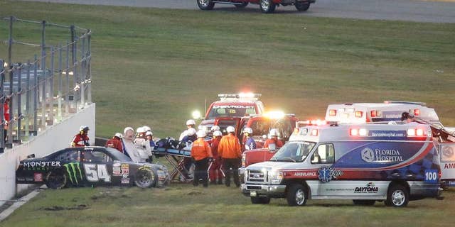 FILE - In this Feb. 21, 2015, file photo, Kyle Busch, center, is taken to an ambulance on a stretcher after he was involved in a multi-car crash during the Xfinity series auto race at Daytona International Speedway in Daytona Beach, Fla. He knew it was going to be bad when his car slid through the grass into the wall, and he knew immediately that both his leg and foot were broken. (AP Photo/John Raoux, File)