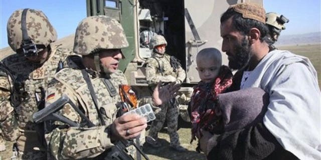 January 28, 2012: A German medic and soldier, center, part of a mobile medical team in the NATO- led International Security Assistance Force (ISAF) explains the usage of the medicine to father of an Afghan child patient during a joining ceremony of Taliban militants with the Afghan government in Baghlan, north of Kabul, Afghanistan.