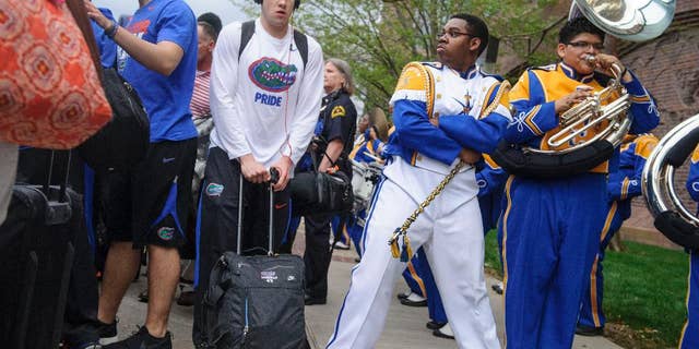 Florida's Billy Donovan, center left, walks past drum major Khyree Henderson, second from right, and the Townview Marching Band outside a hotel in Dallas on Wednesday, April 2, 2014. Florida plays Connecticut on Saturday in the semifinals of the NCAA men's college basketball tournament in Arlington, Texas. (AP Photo/The Dallas Morning News, Matthew Busch) MANDATORY CREDIT; MAGS OUT; TV OUT; INTERNET USE BY AP MEMBERS ONLY; NO SALES