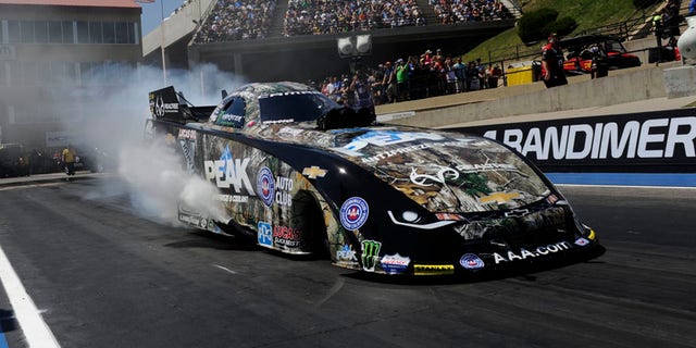 In this photo provided by NHRA, John Force prepares for a run in Funny Car during the Mopar Mile-High NHRA Nationals.