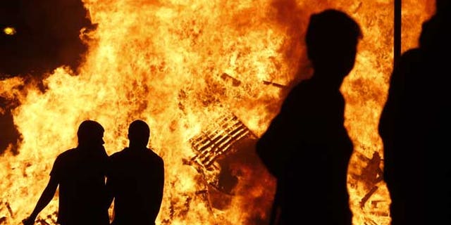 July 11, 2013: Loyalists watch a bonfire in the Sandy Row area of Belfast, Northern Ireland. Hundreds of fires were set alight Thursday as loyalists celebrate the July 12, remembering the defeat of the Catholic King James, by the Protestant William of Orange in 1690.