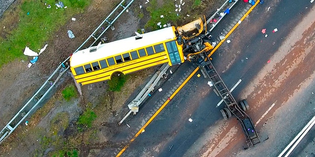 In this aerial photo, a school bus lies crashed on Route 80 in Mount Olive, N.J., Thursday, May 17, 2018. The Paramus school district says the bus was taking students on Thursday from East Brook Middle School to Waterloo Village, a historic site near the crash scene. The yellow school bus was carrying 38 students and seven adults when it crashed, killing a student and a teacher.
