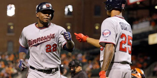 Minnesota Twins' Miguel Sano, left, fist-bumps teammate Byron Buxton after scoring on a bases-loaded walk to Eduardo Nunez during the fourth inning of a baseball game against the Baltimore Orioles, Friday, Aug. 21, 2015, in Baltimore. (AP Photo/Patrick Semansky)
