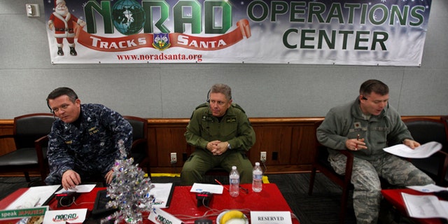 FILE 2012: NORAD Deputy Commander Lt. General Alain Parent, center, of the Royal Canadian Air Force, takes phone calls from children asking where Santa is and when he will deliver presents to their house, during the annual NORAD Tracks Santa Operation, at the North American Aerospace Defense Command, or NORAD, at Peterson Air Force Base, in Colorado Springs, Colo.