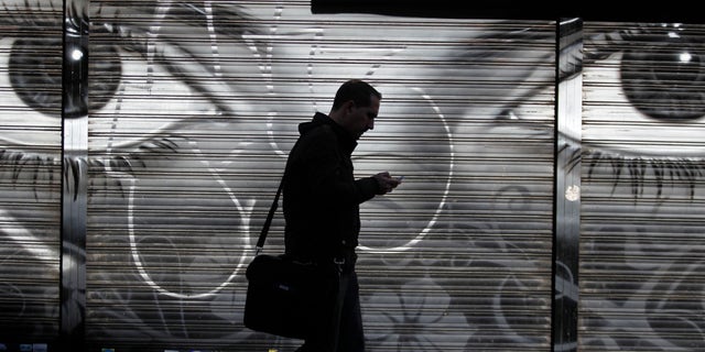 FILE - In this Thursday, Oct. 31, 2013, file photo, a man looks at his cellphone as he walks on the street in downtown Madrid. The National Security Agency tracks the locations of nearly 5 billion cellphones every day overseas, including those belonging to Americans abroad, The Washington Post reported Wednesday, Dec. 4, 2013. Such data means the NSA can track the movements of almost any cellphone around the world, and map the relationships of the cellphone user. (AP Photo/Francisco Seco, File)