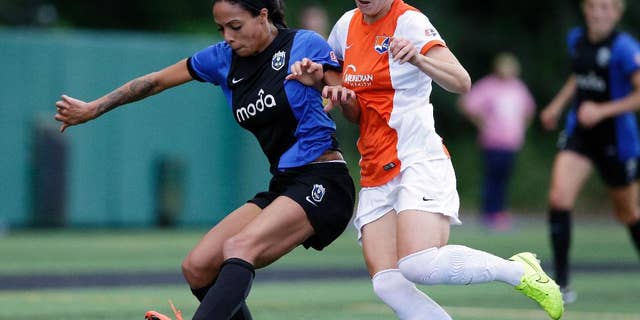 FILE - In this June 28, 2014, file photo, Seattle Reign's Sydney Leroux, left, and Sky Blue's Sophie Schmidt vie for the ball in the first half of an NWSL soccer game in Seattle. In the space of about a week, a group of players from the U.S. team wrapped up the regular season with their National Women’s Soccer League teams, got together for an international friendly against Switzerland, and now face off in the NWSL playoffs. The country’s top players are maintaining a delicate balance between supporting the NWSL at home while gearing up for a busy two years that include the women’s World Cup in Canada next summer and then 2016 Rio Olympics. (AP Photo/Elaine Thompson, File)