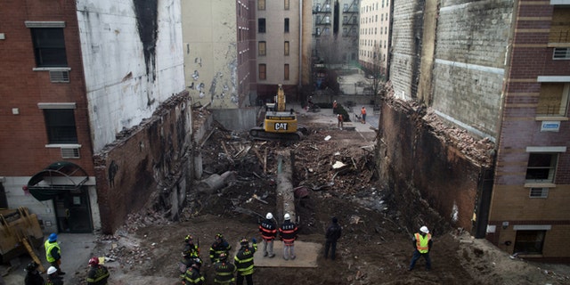 Workers stand beside the recently cleared basement of the two buildings leveled by an explosion on Wednesday in the East Harlem neighborhood of New York, Sunday, March 16, 2014. A pair of congregations gathered to mourn Sunday, one for its lost church and one for two members who lost their lives in the massive explosion. (AP Photo/John Minchillo)