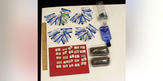 In this undated photo provided by the New York City Department of Investigation, contraband smuggled by an undercover investigator into Rikers Island jail facilities is shown. During six visits to the New York City jail, the investigator was able to get a plastic bag containing 250 glassine envelopes of heroin; one plastic bag containing 24 packaged strips of suboxone; two plastic bags containing a total weight of one half-pound of marijuana, 16 ounces of vodka in a water bottle, and one razor blade past the personnel at the security entrance. (AP Photo/New York City Department of Investigation)