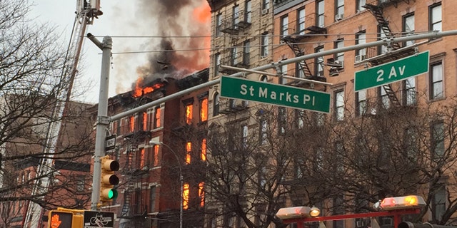 New York City firefighters work the scene of a large fire and a partial building collapse in the East Village neighborhood of New York on Thursday, March 26, 2015. Orange flames and black smoke are billowing from the facade and roof of the building near several New York University buildings. (AP Photo/Suzanne Mitchell)