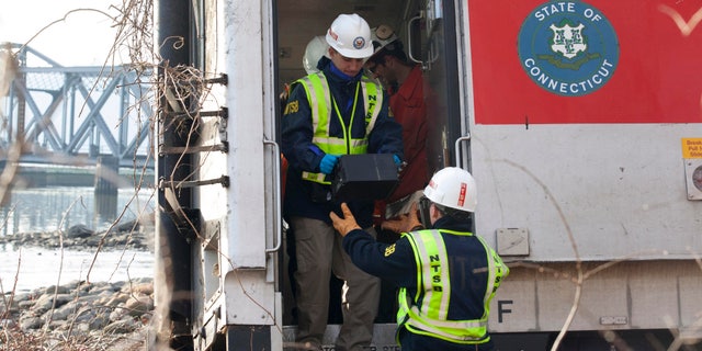 NTSB investigator George Haralampopoulous hands a data recorder down to Mike Hiller from the derailed Metro-North train in the Bronx borough of New York, on Dec 1, 2013.