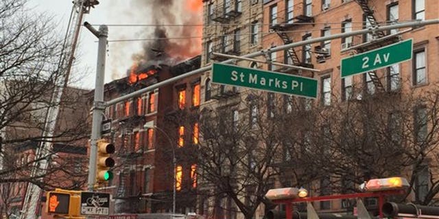 New York City firefighters work the scene of a large fire and a partial building collapse in the East Village neighborhood of New York on Thursday, March 26, 2015. Orange flames and black smoke are billowing from the facade and roof of the building near several New York University buildings. (AP Photo/Suzanne Mitchell)