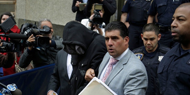 Wojciech Braszczok, center left, with face covered, leaves the courthouse in New York, Wednesday, Oct. 9, 2013. Braszczok, an undercover police detective, was charged with gang assault in a motorcycle rally that descended into violence in New York. (AP Photo/Seth Wenig)