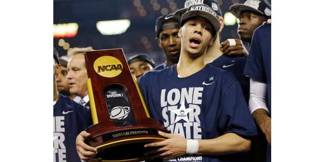 April 7, 2014: Connecticut guard Shabazz Napier holds the championship trophy after defeating Kentucky 60-54, at the NCAA Final Four tournament college basketball championship game in Arlington, Texas. (AP Photo/David J. Phillip)