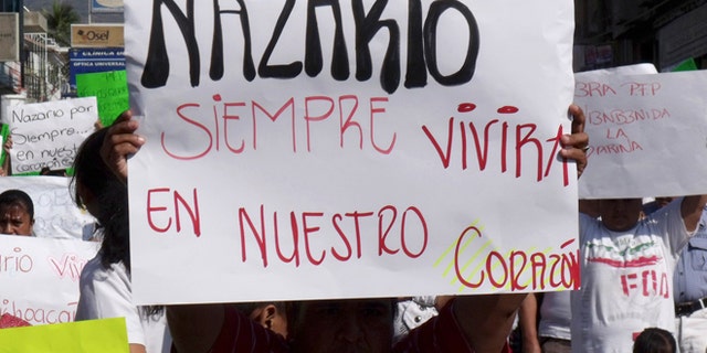FILE - In this Dec. 12, 2010 file photo, a man holds a sign that reads in Spanish "Nazario will always live in our hearts," referring to La Familia drug cartel leader Nazario Moreno Gonzalez during a demonstration after the government announced he was killed in Apatzingan, Mexico. Years later on Sunday, March 9, 2014, officials say they are trying to determine if a man killed in an early morning shootout is Moreno. Some residents of Michoacan have reported seeing Moreno as his former cartel, La Familia Michoacana, was morphing into the more vicious and powerful Knights Templar. (AP Photo/Primera Plana, File)