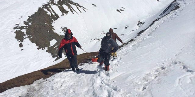 October 17, 2014: In this handout photo provided by the Nepalese army, rescue team members carry the body of an avalanche victim at Thorong La pass area. (AP Photo/Nepalese Army)
