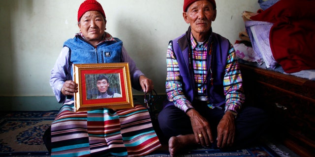 April 23, 2014: Nimdige Sherpa holds a portrait of her son Ang Kaji Sherpa, killed in an avalanche on Mount Everest, with her husband Ankchu Sherpa seated beside her in their rented apartment in Katmandu, Nepal. (AP)