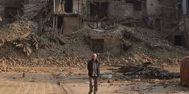 May 25, 2015: A Nepalese man walks past damaged houses one month after the deadly 7.8 magnitude earthquake in Kathmandu, Nepal.