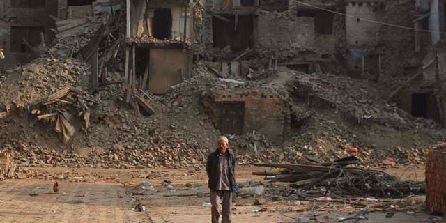 May 25, 2015: A Nepalese man walks past damaged houses one month after the deadly 7.8 magnitude earthquake in Kathmandu, Nepal.