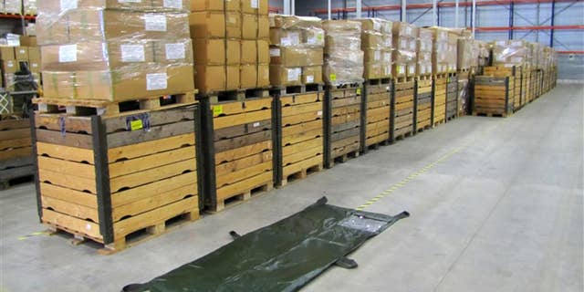 In this undated but recent handout photo provided by BVA-Auctions.com, a body bag is displayed next to pallets containing about 2500 body bags put up for auction by the Dutch government Thursday, Oct. 2, 2014. Call it an offer to die for. The government is selling off 2,500 body bags in an online auction. Rob Meijer, commercial director of BVA Auctions, said Thursday his company sells plenty of strange stuff, but "this is special." The bags are being sold in a single lot, which has a reserve price of 4,000 euros (usd 5,050). The auction closes on Oct. 6. (AP Photo/BVA-Auctions.com, HO)