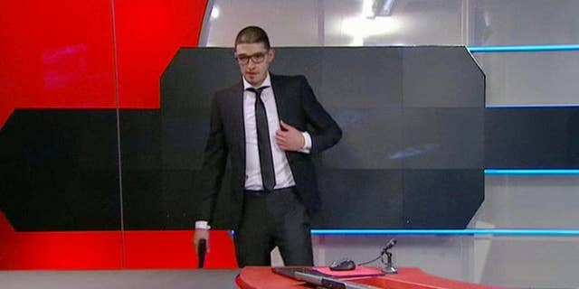 Police arrived to storm the studio out of sight of the camera and order 19-year-old gunman to drop his weapon, after he stormed into the headquarters of Dutch national broadcaster NOS demanding TV airtime Thursday night Jan. 29, 2015, is shown on video recorded at the time as he waits at the TV station broadcast studio in Hilversum, Netherlands.  The man claims to be from a "hackers' collective," according to a reporter who spoke to the man during his raid on the TV station offices, causing NOS to go off-air for around an hour. (AP Photo / NOS TV) NETHERLANDS OUT - TV OUT