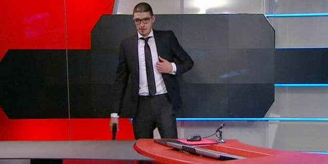 Police arrived to storm the studio out of sight of the camera and order 19-year-old gunman to drop his weapon, after he stormed into the headquarters of Dutch national broadcaster NOS demanding TV airtime Thursday night Jan. 29, 2015, is shown on video recorded at the time as he waits at the TV station broadcast studio in Hilversum, Netherlands. The man claims to be from a "hackers' collective," according to a reporter who spoke to the man during his raid on the TV station offices, causing NOS to go off-air for around an hour. (AP Photo / NOS TV) NETHERLANDS OUT - TV OUT